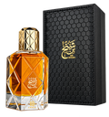 A faceted glass perfume bottle filled with amber-orange liquid, shown beside a black rectangular presentation box with a gold honeycomb texture and gold Arabic script reading BIN SHAKKH.