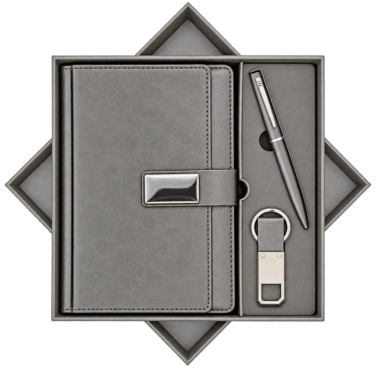 A gray gift set presented in an open geometric box, containing a textured gray notebook with a silver clasp, a matching gray pen, and a small gray and silver keychain or USB-style accessory, all arranged on a white background.